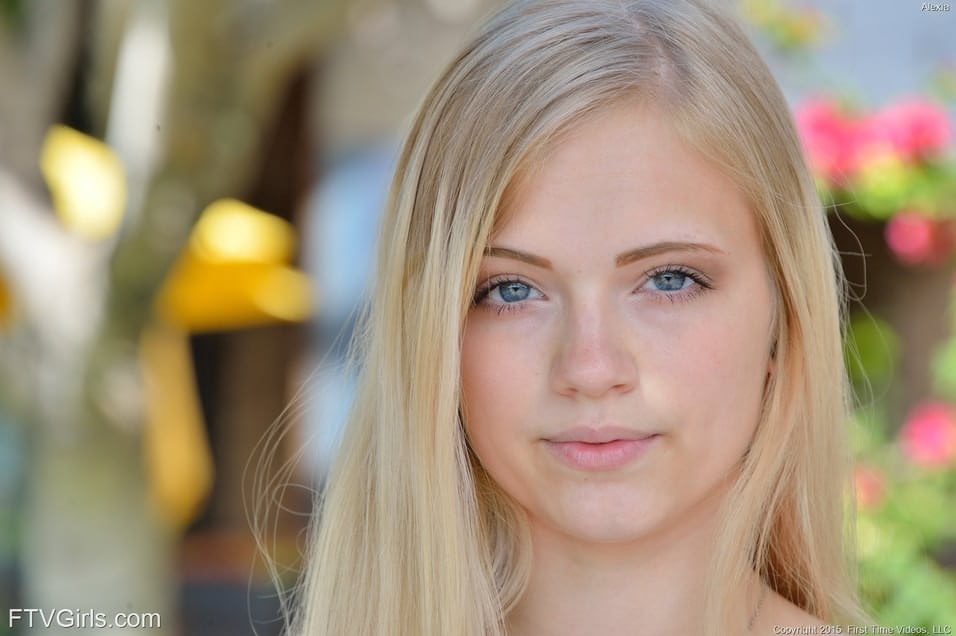 Junge Teenagerin mit hübschem Gesicht, die im Park mit gespreizten Beinen einen Blick unter ihren Rock gewährt