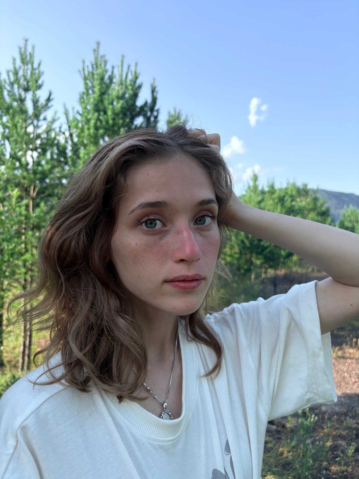 Ein Mädchen mit heller Haut und Sommersprossen zeigt sich im Freien mit ihren Tattoos