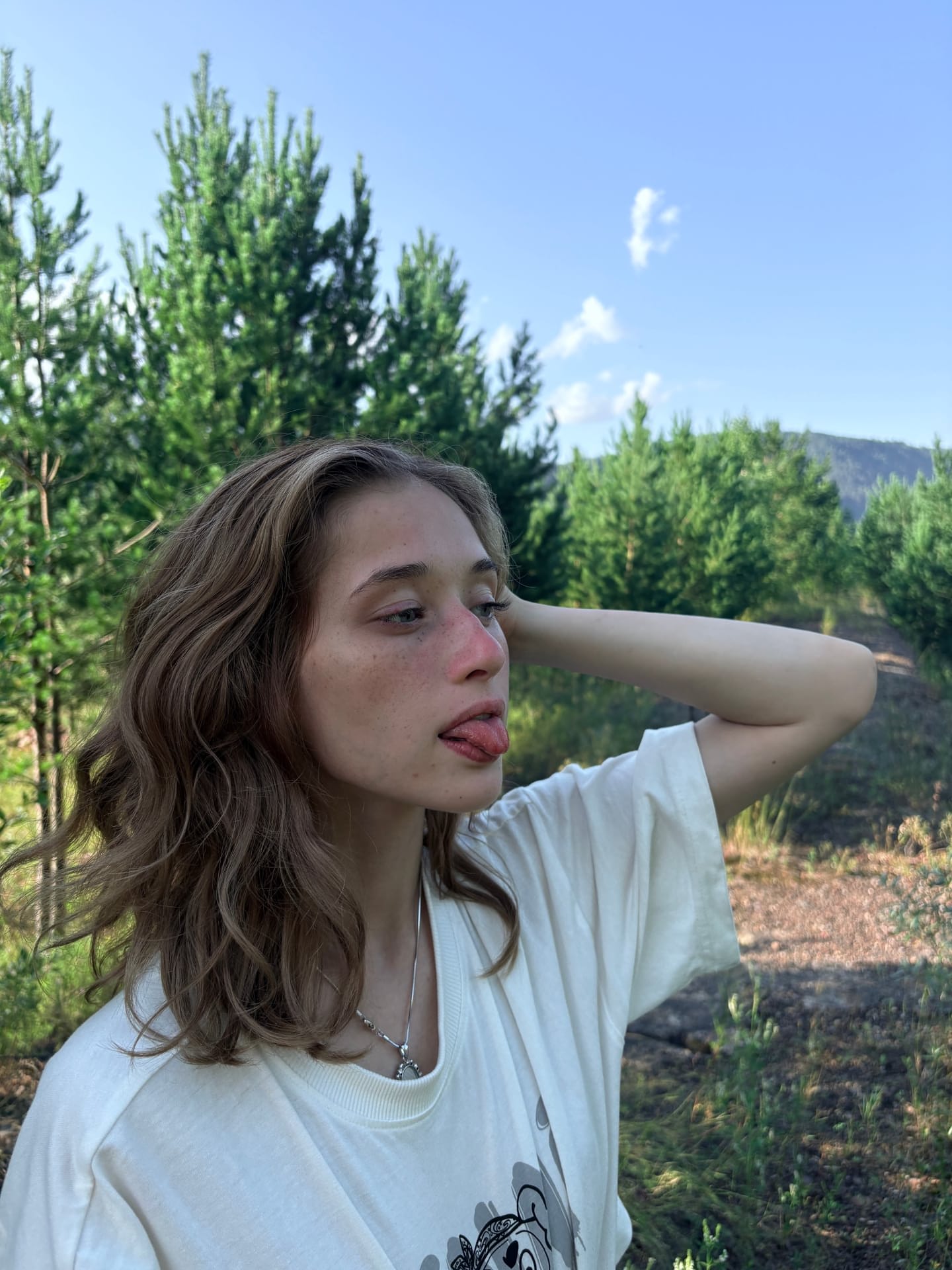 Ein Mädchen mit heller Haut und Sommersprossen zeigt sich im Freien mit ihren Tattoos