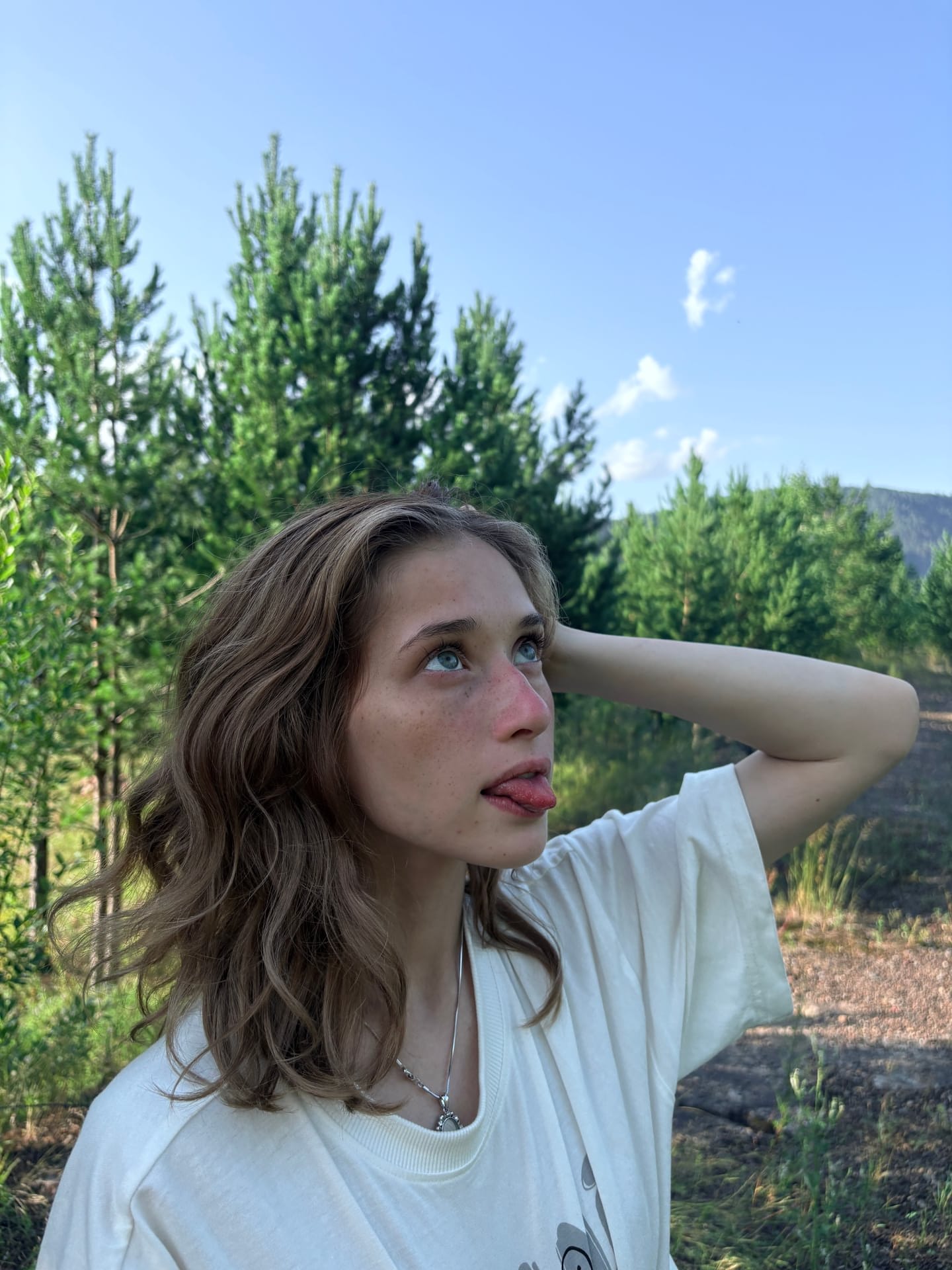 Ein Mädchen mit heller Haut und Sommersprossen zeigt sich im Freien mit ihren Tattoos