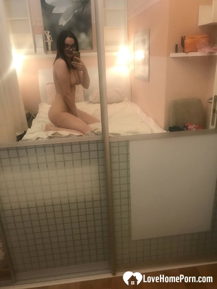 Brünette mit Brille macht Nacktfotos, auf denen sie ihre kleinen Brüste und ihre rasierte Muschi zeigt