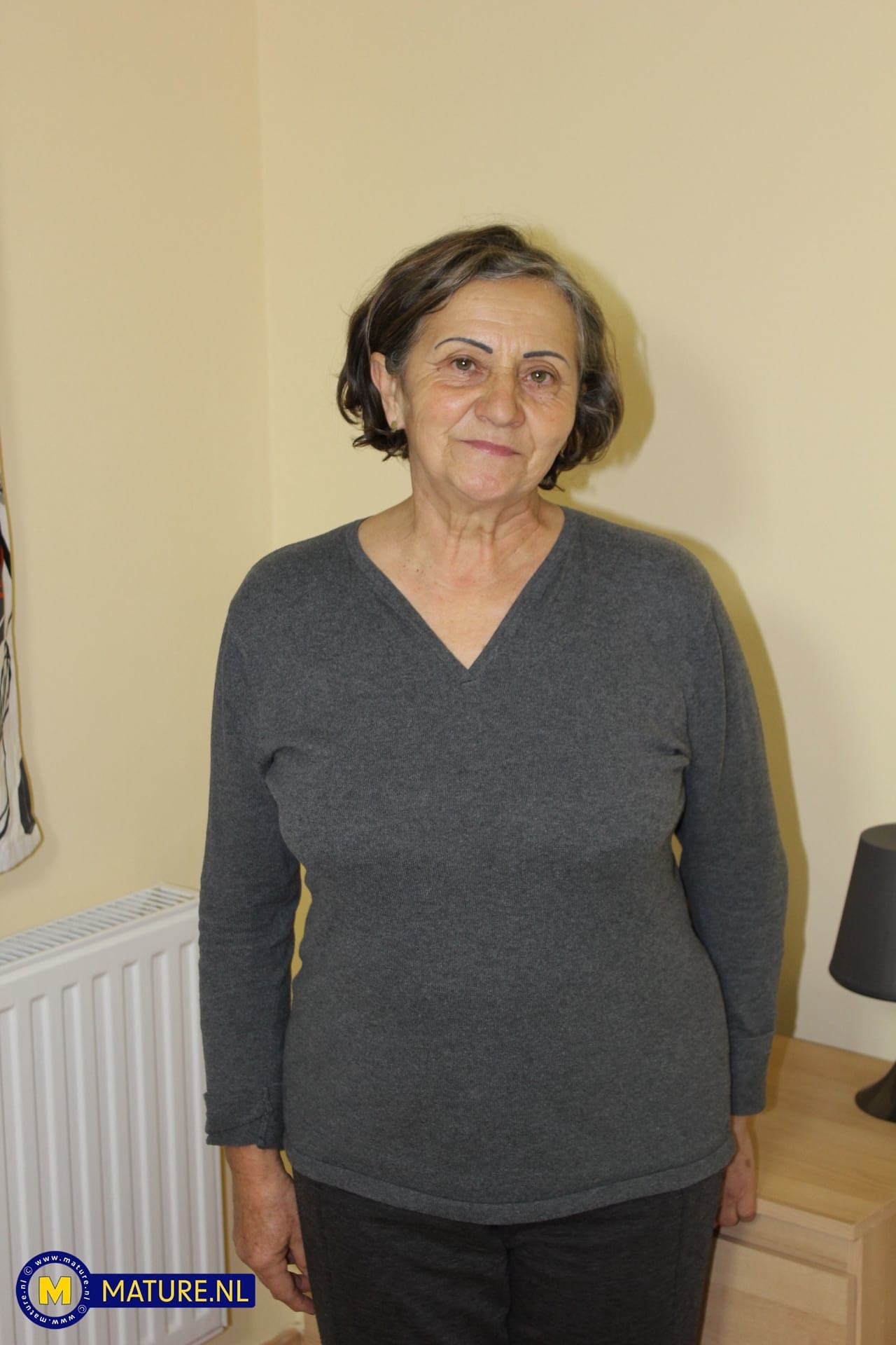 Oma Jana W zieht sich komplett aus und zeigt ihre behaarte Muschi auf einem Bett