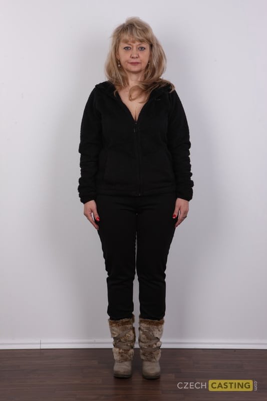 Eine ältere Blondine mit einem kleinen Bauch zieht sich für ihr Nackt-Debüt komplett aus