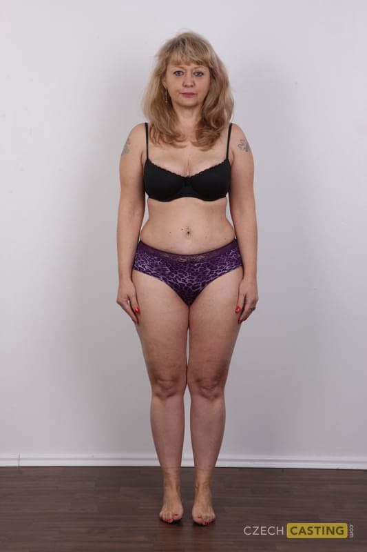 Eine ältere Blondine mit einem kleinen Bauch zieht sich für ihr Nackt-Debüt komplett aus