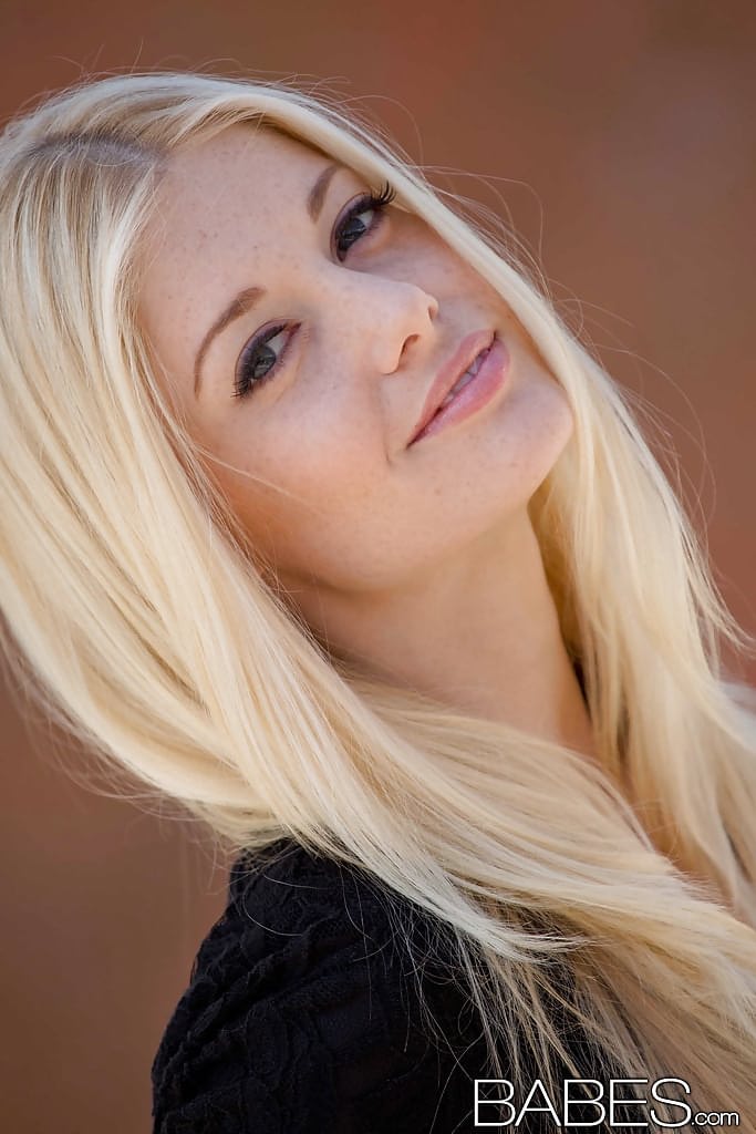 Eine unglaublich hübsche Blondine in schwarzen Nylons, die im Freien ihre schlanken Kurven zeigt