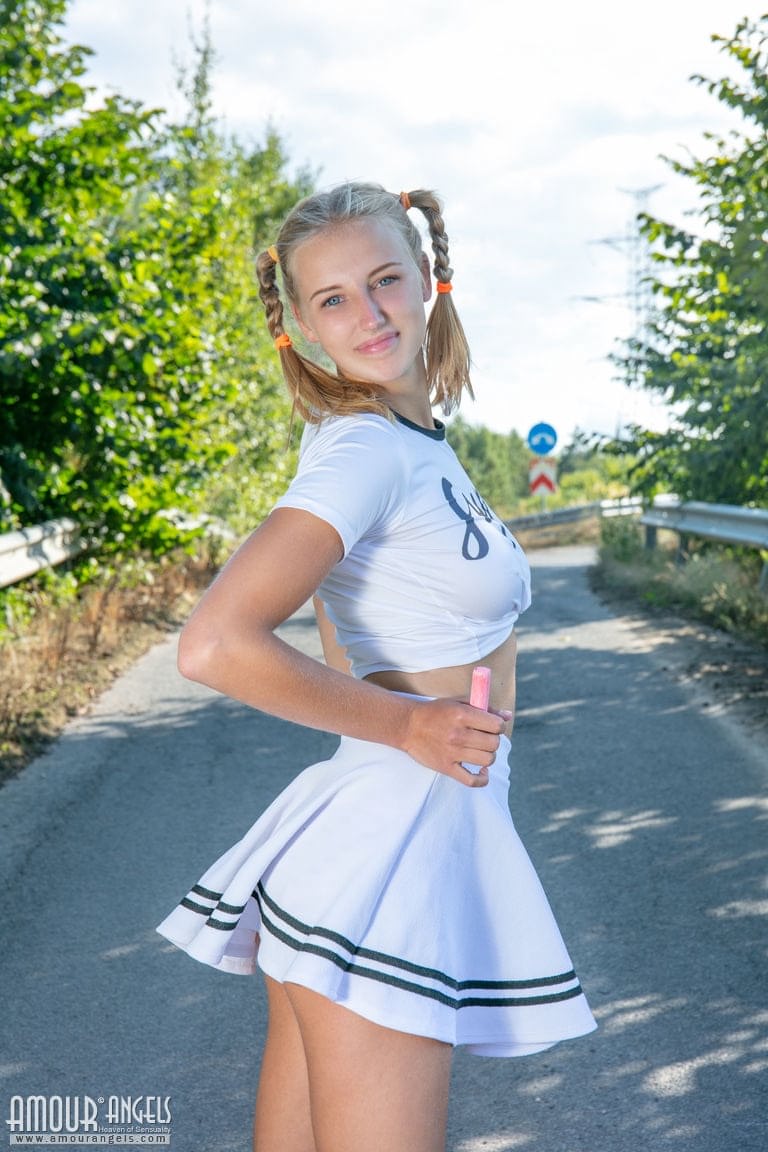Die blonde Teenagerin Nana zieht sich auf einer asphaltierten Straße bis auf ihre Socken und Turnschuhe aus