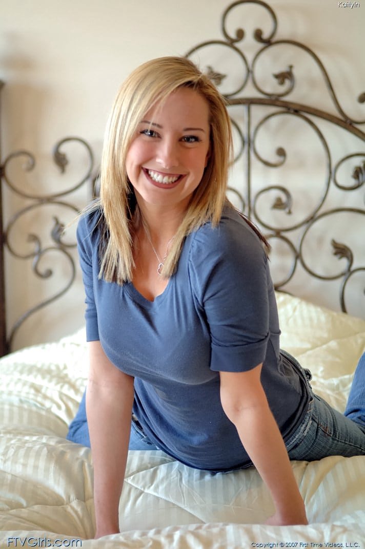 Das Glamour-Babe mit dem wunderschönen Lächeln, Kaitlyn, spielt auf ihrem Bett an ihrer rasierten Muschi herum